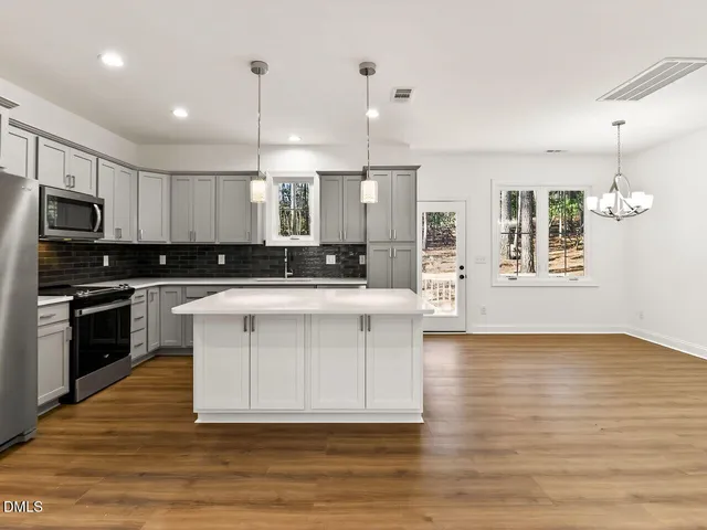 a kitchen with stainless steel appliances kitchen island wooden floors and white cabinets