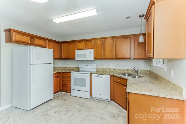 a kitchen with stainless steel appliances granite countertop a refrigerator a stove top oven a sink and dishwasher