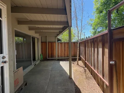 a view of backyard with wooden fence and large trees