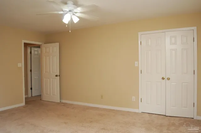 a view of an empty room and chandelier fan