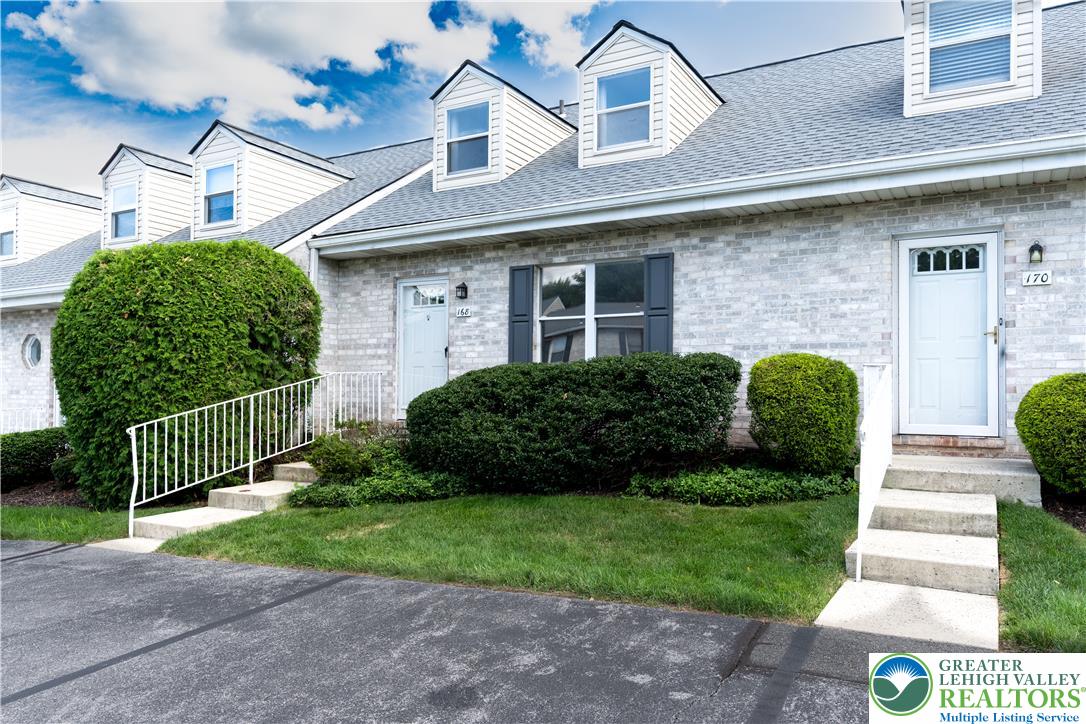 168 Springhouse Road Allentown, PA 18104 - Photo 2 of 49 Charming townhome with dormer windows and verdant landscaping, offering welcoming curb appeal.