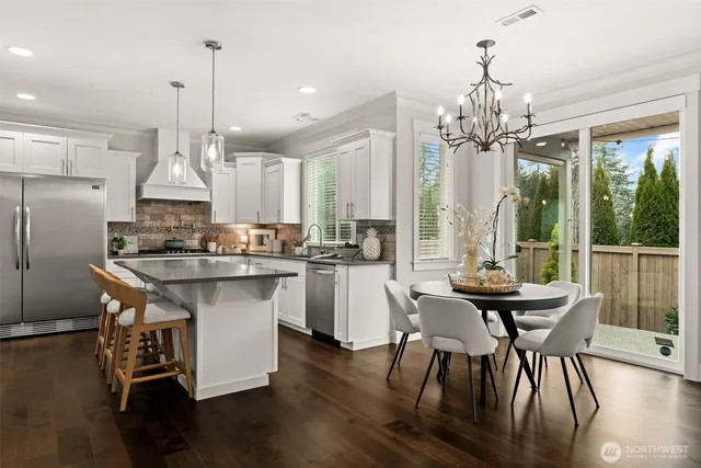 a kitchen with stainless steel appliances granite countertop a table chairs stove and kitchen view
