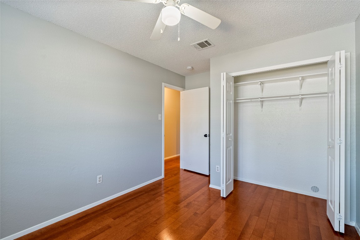 14433 Robert I Walker Boulevard Austin, TX 78728 - Photo 13 of 15 Unfurnished bedroom featuring dark wood-style floors, a textured ceiling, ceiling fan, and a closet