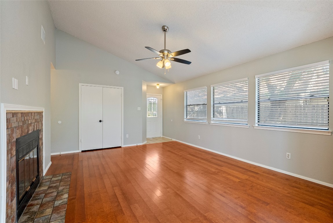 14433 Robert I Walker Boulevard Austin, TX 78728 - Photo 4 of 15 Unfurnished living room featuring a glass covered fireplace, hardwood / wood-style flooring, high vaulted ceiling, and ceiling fan