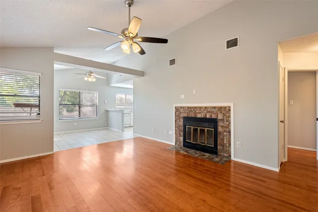an empty room with wooden floor fireplace and windows