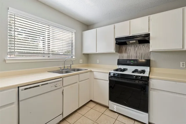 a kitchen with cabinets appliances a sink and a window