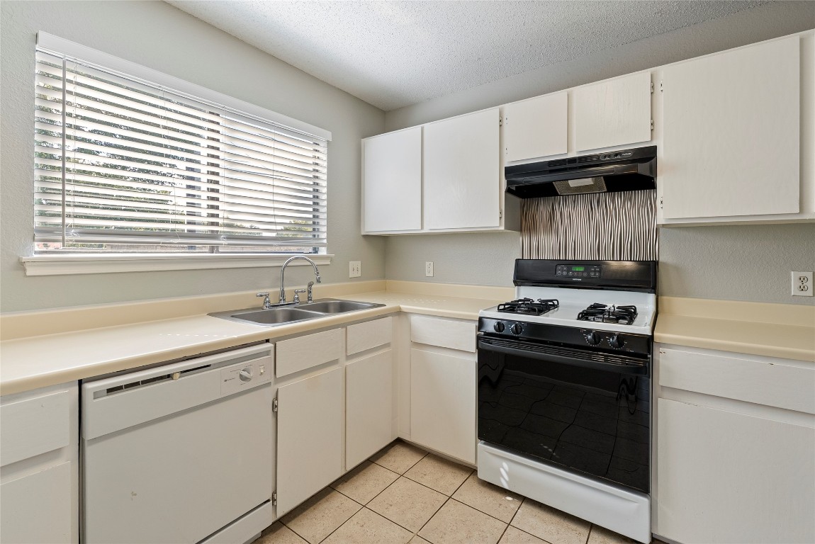 14433 Robert I Walker Boulevard Austin, TX 78728 - Photo 7 of 15 Kitchen featuring range with gas cooktop, light countertops, white dishwasher, white cabinets, and extractor fan