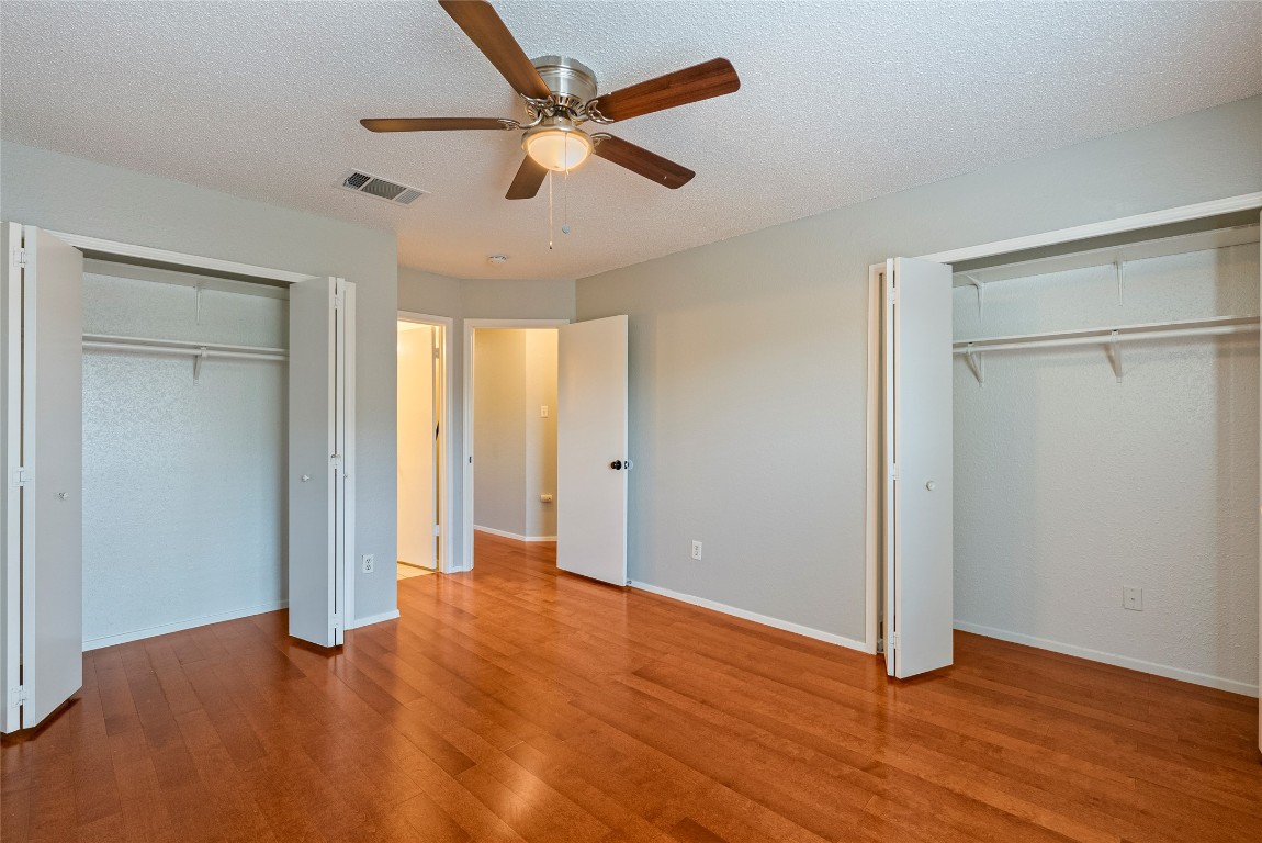 14433 Robert I Walker Boulevard Austin, TX 78728 - Photo 10 of 15 Unfurnished bedroom featuring two closets, a textured ceiling, light wood-type flooring, and ceiling fan