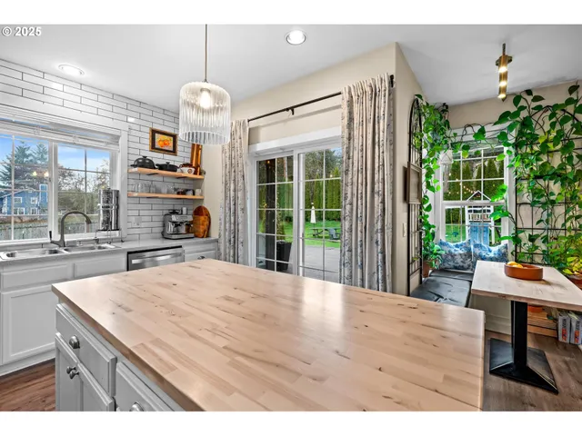 a room with kitchen island a large window cabinets and stainless steel appliances