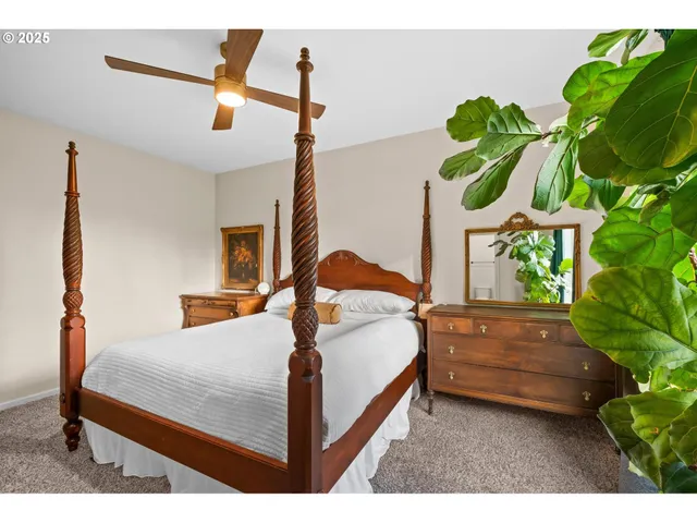 a bedroom with a bed a dresser and a potted plant