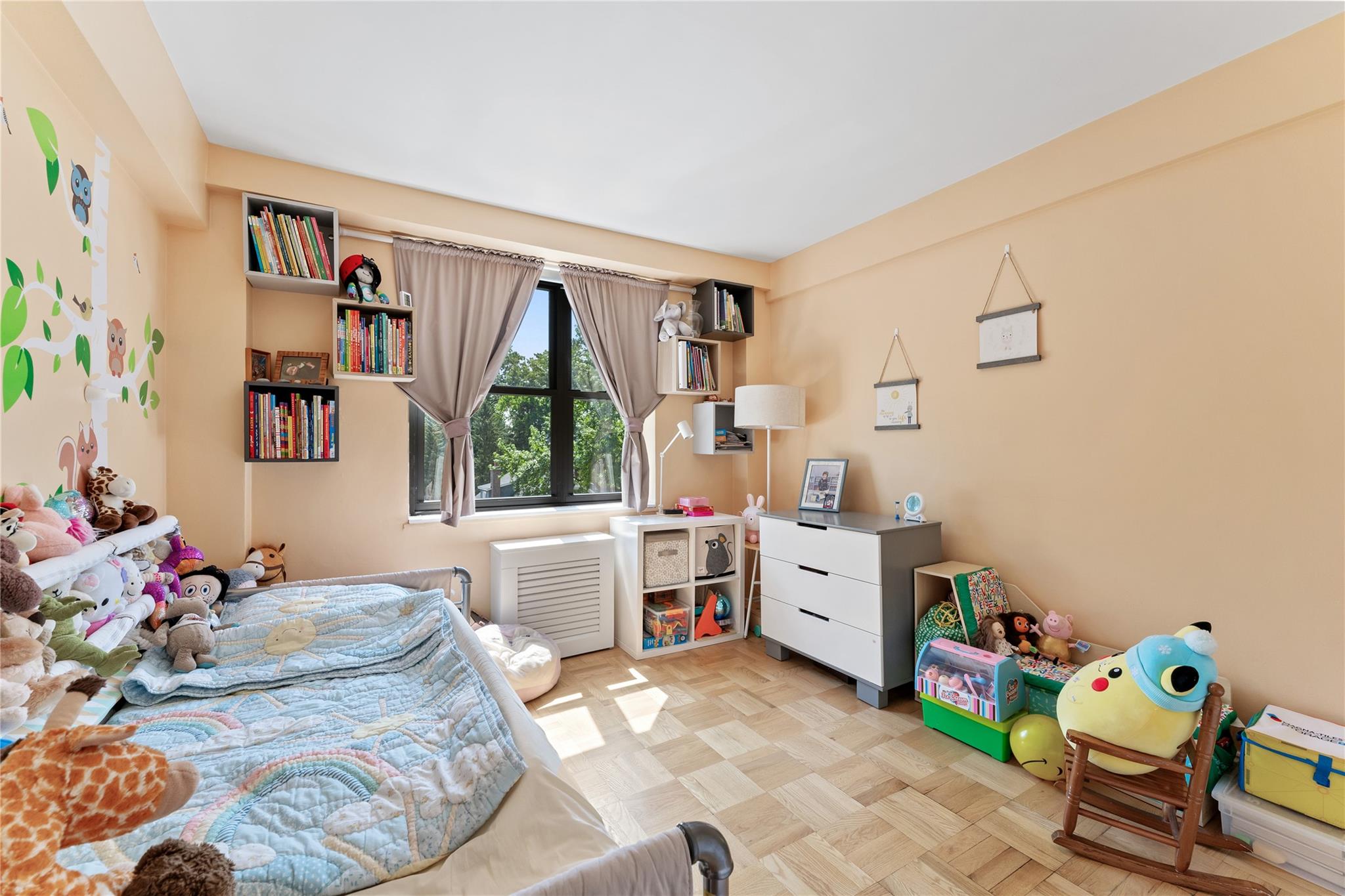 3103 Fairfield Avenue, Unit 5D Bronx, NY 10463 - Photo 9 of 13 a room with a baby bed a couch and a window