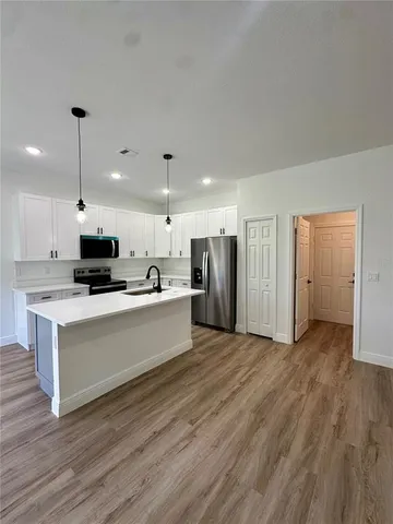 a view of kitchen with stainless steel appliances refrigerator stove microwave and cabinets
