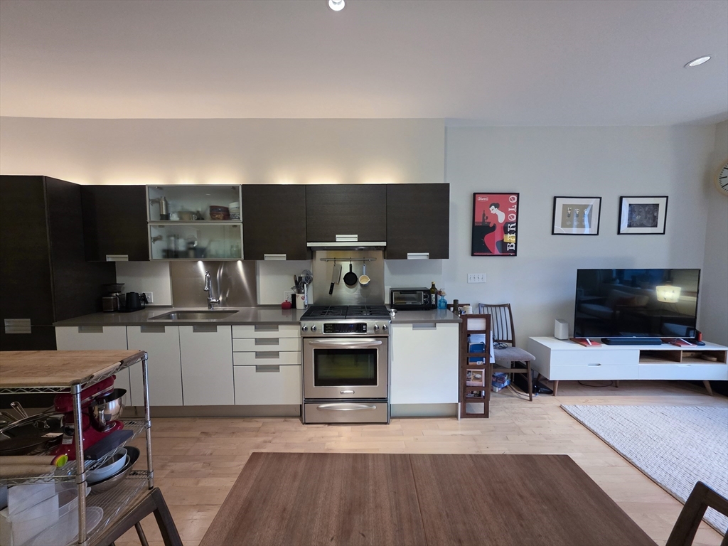346-354 Congress Street, Unit 505 Boston, MA 02210 - Photo 3 of 14 a kitchen with stainless steel appliances a stove top oven a sink dishwasher and a refrigerator with wooden floor