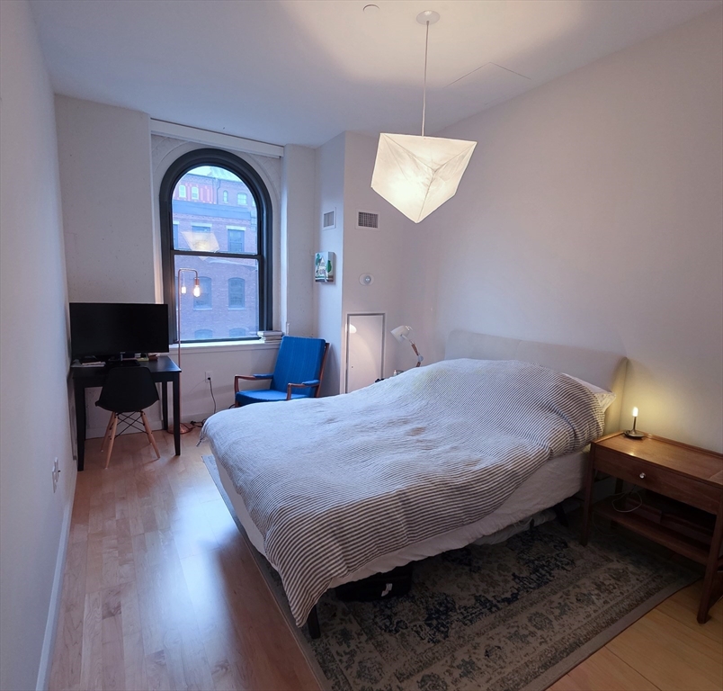 346-354 Congress Street, Unit 505 Boston, MA 02210 - Photo 6 of 14 a bedroom with a bed and a chandelier