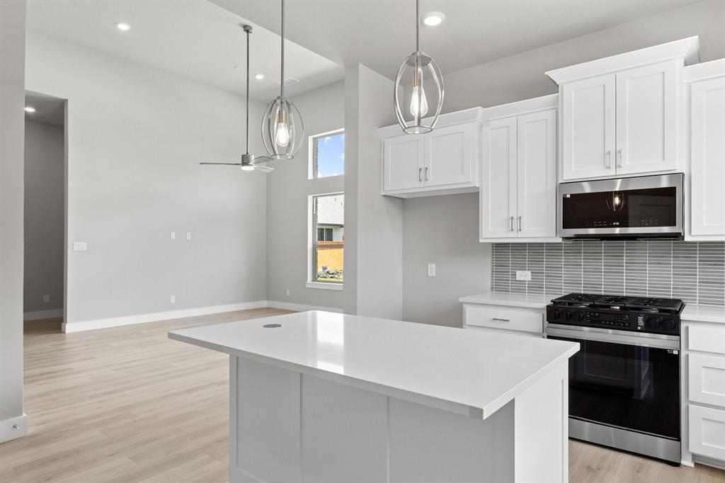 8517 Del Rio Trail Wylie, TX 75098 - Photo 13 of 30 a kitchen with stainless steel appliances a stove a microwave and white cabinets
