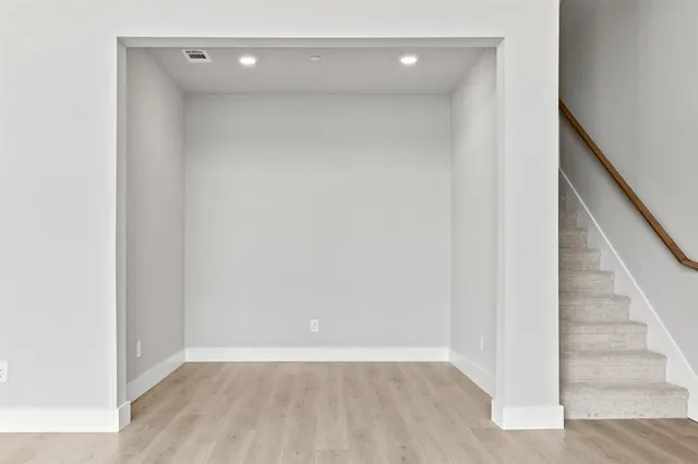a view of an empty room with stairs and a hallway