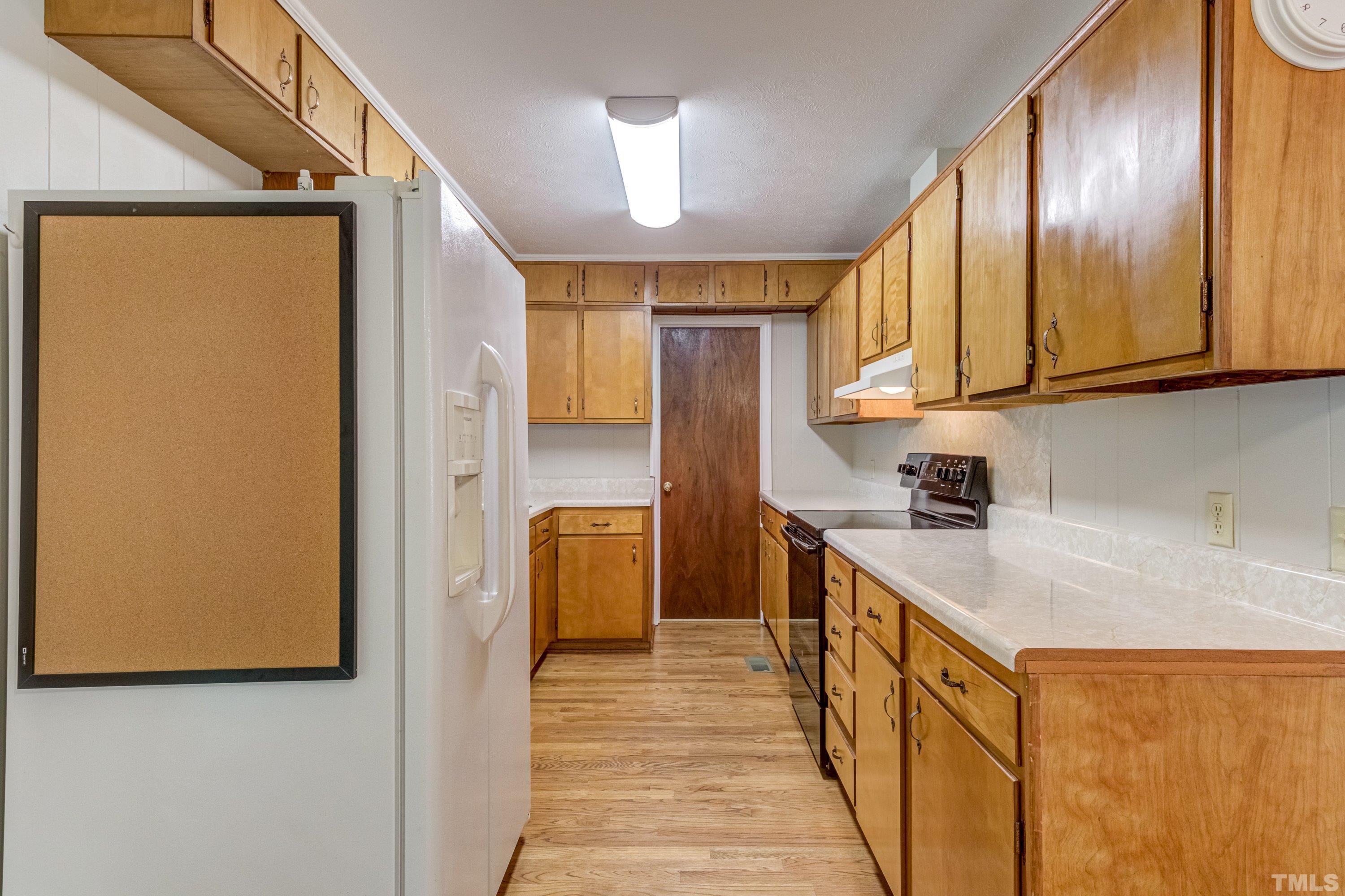 128 Spring Lane Lillington, NC 27546 - Photo 28 of 42 a kitchen with stainless steel appliances granite countertop a refrigerator a sink dishwasher and wooden cabinets with wooden floor