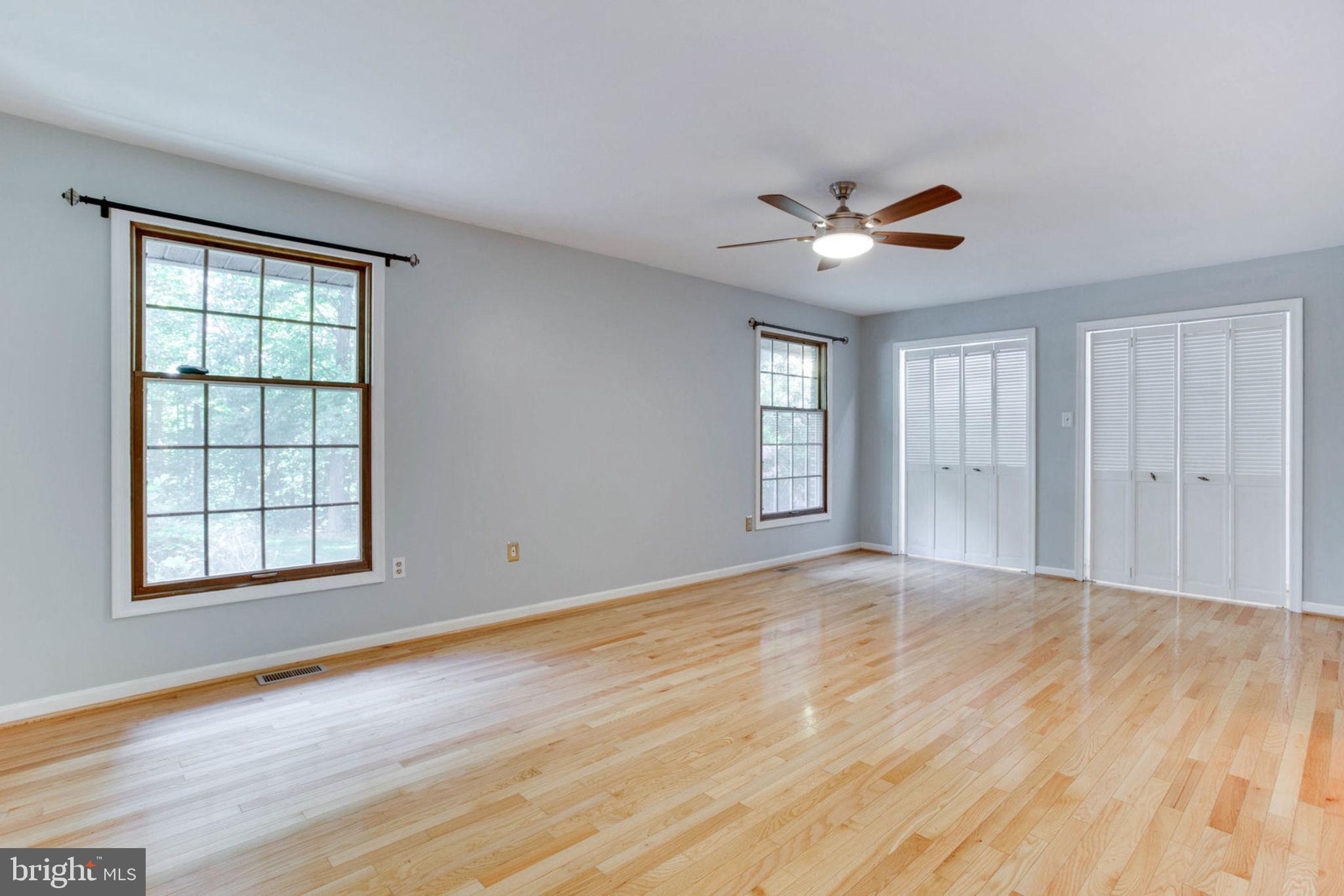 4304 Rousbys Run West River, MD 20778 - Photo 17 of 50 an empty room with wooden floor ceiling fan and windows
