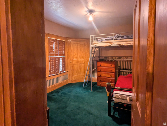 190 North 200 E Street Beaver, UT 84713 - Photo 35 of 40 Interior room featuring deep green carpeting, wooden wall paneling, and a window with plantation shutters