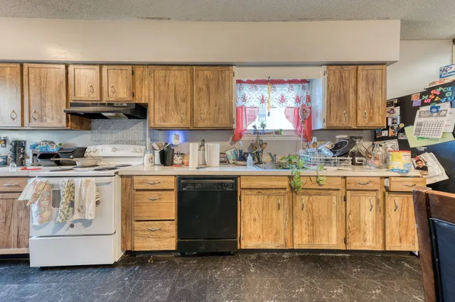 a kitchen with granite countertop a sink cabinets stainless steel appliances and a window
