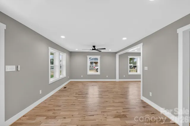 a view of an empty room with window and wooden floor