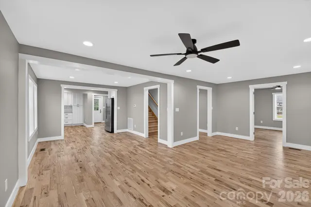 a view of empty room with wooden floor and ceiling fan