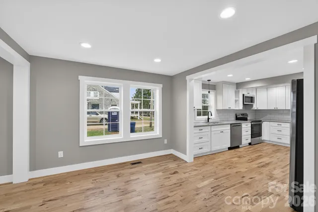 a open kitchen with white cabinets and wooden floor