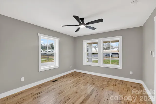a view of an empty room with a window and wooden floor