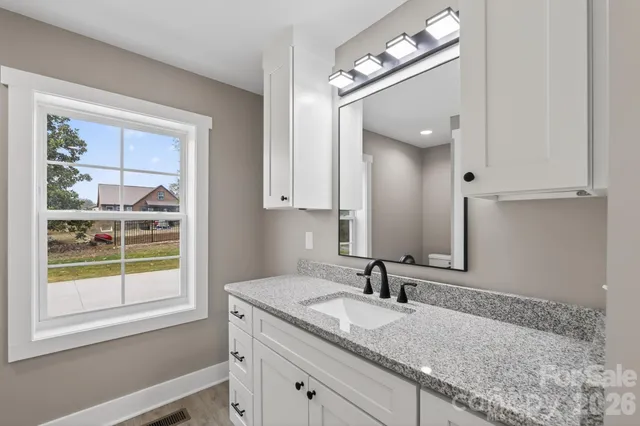 a bathroom with a granite countertop sink and a mirror