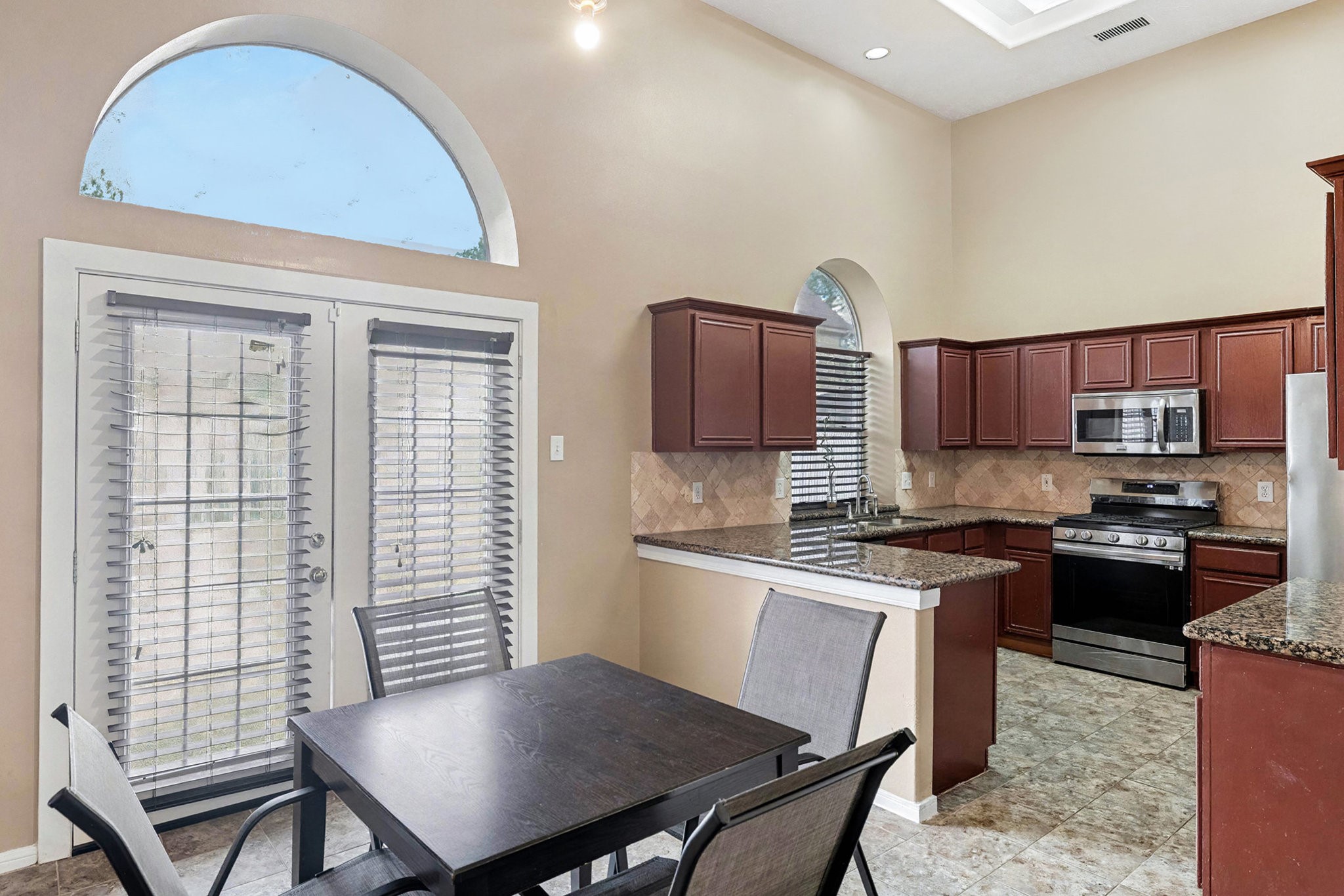 12411 Wright Oaks Drive Houston, TX 77014 - Photo 12 of 29 a kitchen with stainless steel appliances granite countertop a stove a sink dishwasher a microwave oven and a dining table with wooden cabinet