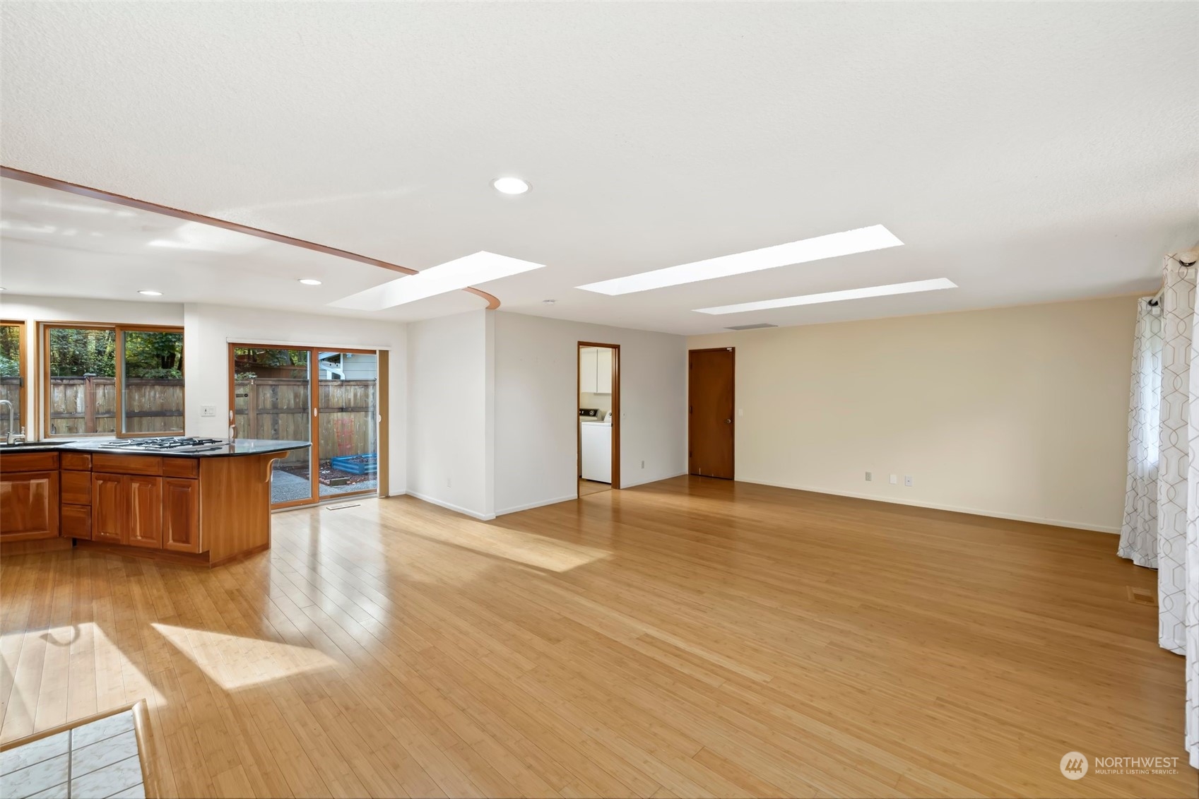 12730 Southeast 95th Place Renton, WA 98056 - Photo 5 of 38 a view of an empty room with wooden floor and a kitchen view