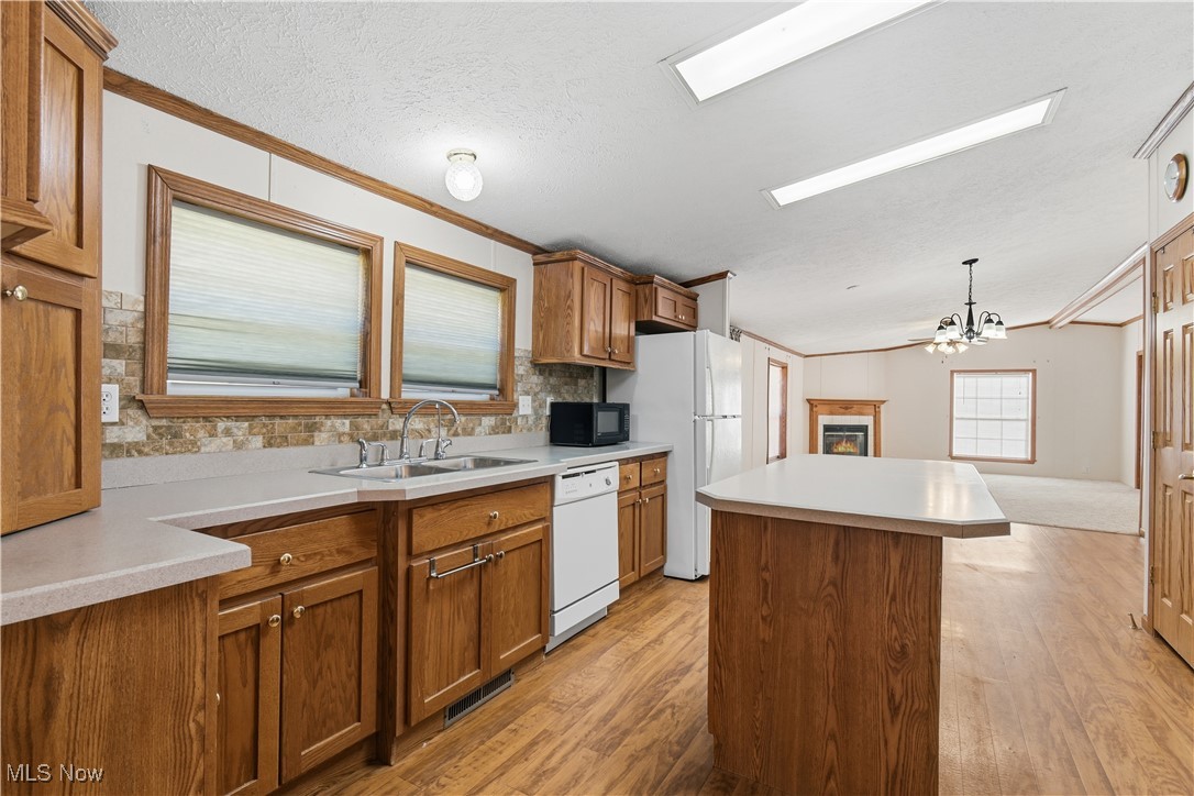 60602 Shaw Road Cambridge, OH 43725 - Photo 12 of 41 Kitchen with brown cabinetry, a kitchen island, light countertops, light wood-type flooring, and ornamental molding