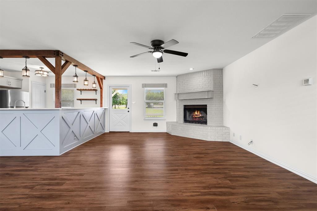 13132 Highway 78 Blue Ridge, TX 75424 - Photo 5 of 35 Spacious open-concept interior featuring wood-finish flooring, a white brick fireplace, and a ceiling fan with integrated lighting