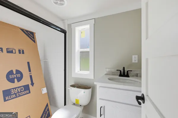 a bathroom with a sink toilet vanity and window