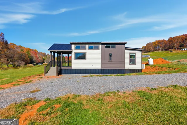 a front view of a house with a yard and mountain view in back