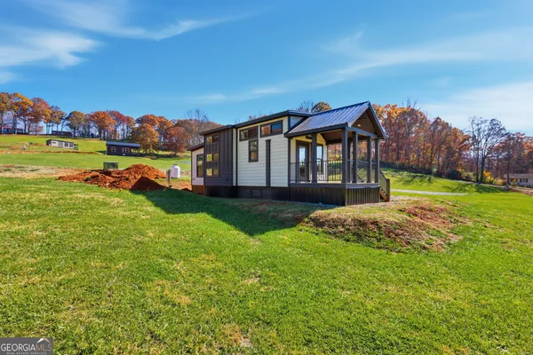 a front view of a house with a yard and mountain