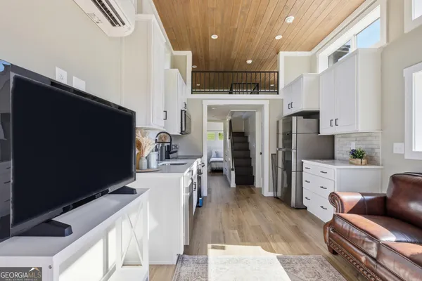 a kitchen with stainless steel appliances kitchen island granite countertop a refrigerator oven a sink dishwasher and white cabinets with wooden floor