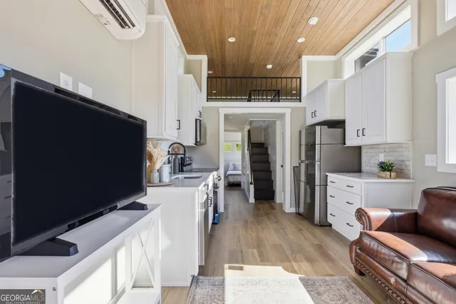 a kitchen with stainless steel appliances kitchen island granite countertop a refrigerator oven a sink dishwasher and white cabinets with wooden floor
