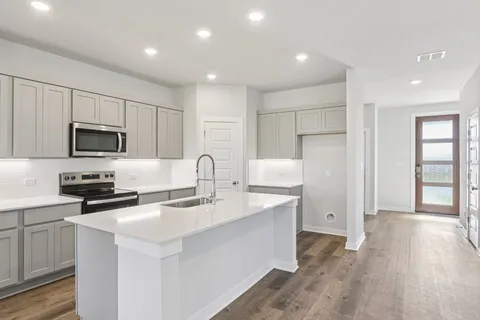 a large kitchen with kitchen island a stove a sink a refrigerator and white cabinets