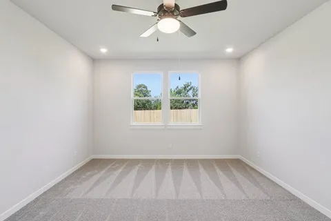 an empty room with a window and a ceiling fan