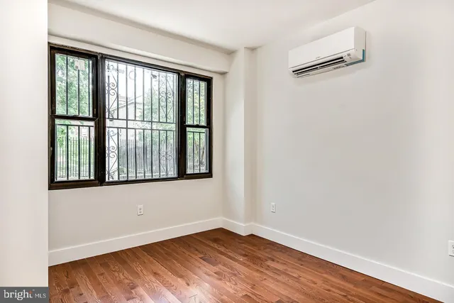 a view of an empty room with wooden floor and a bathroom