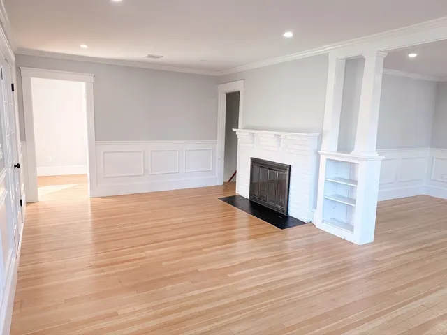 a view of a livingroom with wooden floor and a fireplace