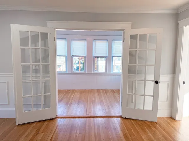 an empty room with wooden floor and windows