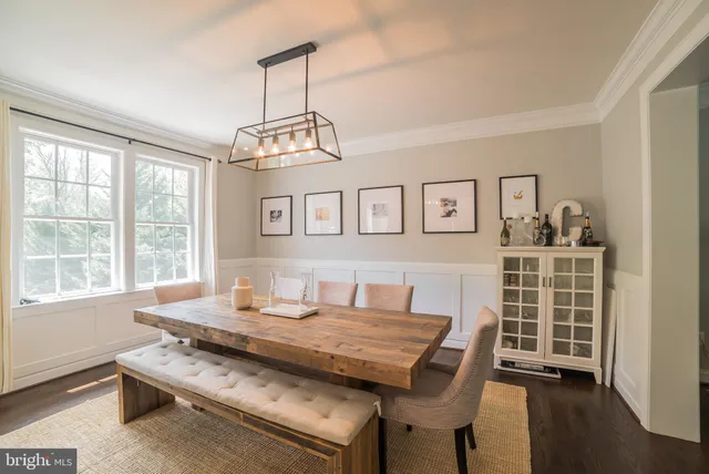 a dining room with wooden floor a chandelier a wooden table and chairs