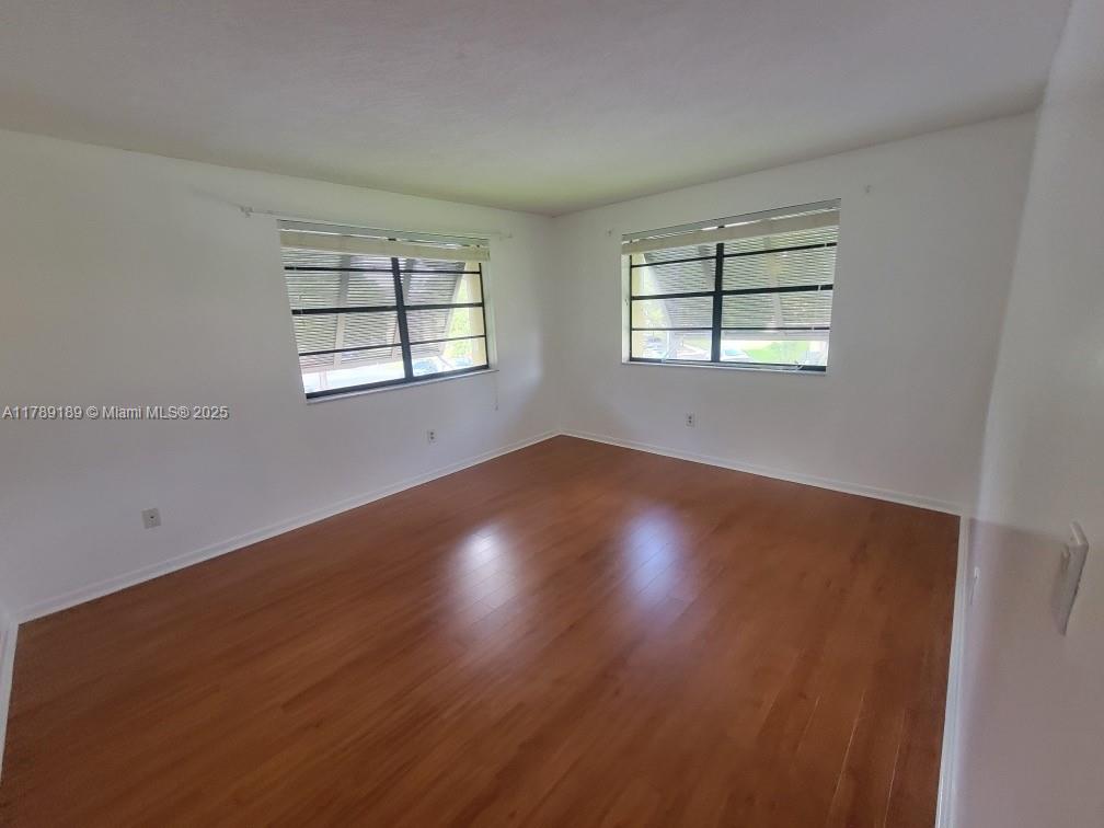 7905 Southwest 86th Street, Unit 626 Miami, FL 33143 - Photo 3 of 8 an empty room with wooden floor and windows