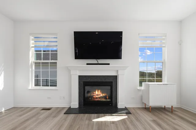 a living room with a fireplace a flat screen tv and windows