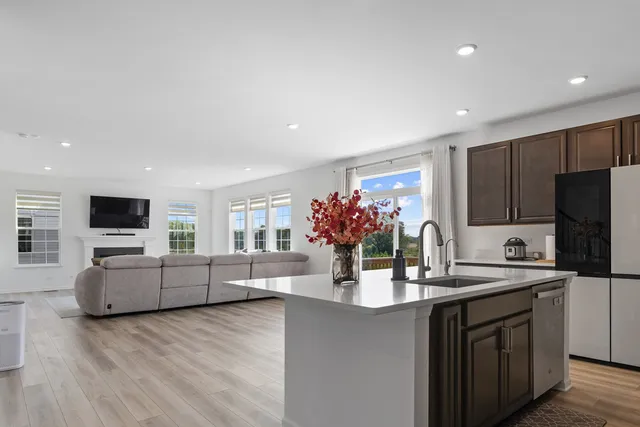 a kitchen with stainless steel appliances kitchen island granite countertop a sink dishwasher a stove and a refrigerator with wooden floor