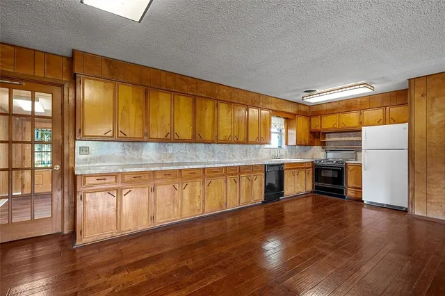 a kitchen with granite countertop wooden floors stainless steel appliances and sink