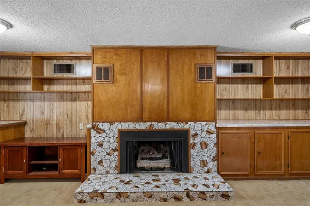 a living room with stainless steel appliances furniture a fireplace and a bookshelf
