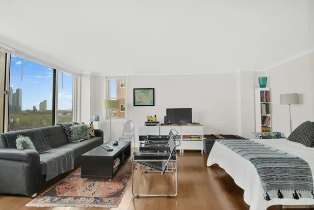 a bedroom with a bed a couch and a flat tv screen on the dresser